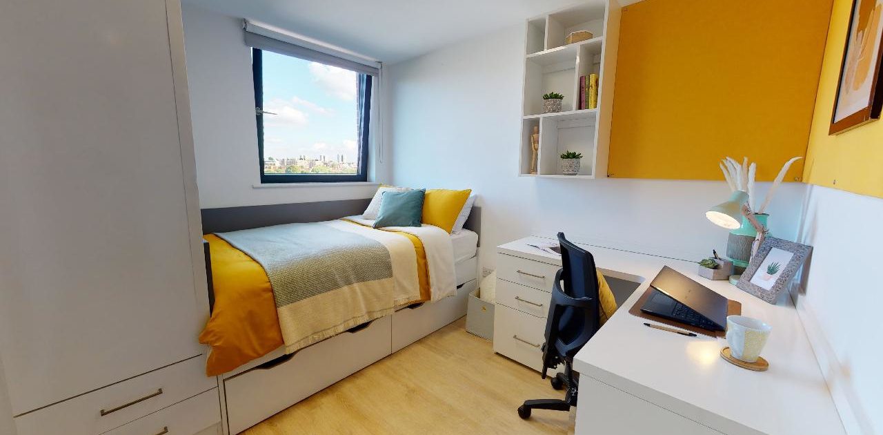A cozy bedroom with yellow walls, hardwood floors, and furniture including a bed, nightstand, chest of drawers, and cupboard is decorated with linens, pillows, window treatments, and a lampshade.