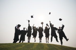 A group of graduates are jumping in the air.
